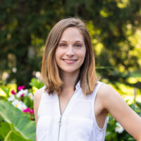 Photograph of Kara Larson outdoors, with green leaves and flowers in the background